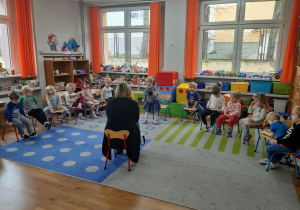 dzieci siedzące w półokregu słuchają bibliotekarki